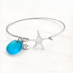 Playful yet refined, the Sea Glass Charm Bracelet is a lovely adornment that captures the essence of the wonders of the seas. Details: Stainless Steel Bangle: 67.5mm x 57mmCharm: Brass With Imitation Rhodium Plating, 19mmOcean Blue Sea Glass, 16.5mmOpen Front Design Fits All Sizes Ocean-inspired Bracelet With Starfish Charm, Ocean-inspired Starfish Charm Bracelet, Elegant Starfish Bracelets For Beach, Adjustable Ocean-inspired Metal Jewelry, Ocean-inspired Bangle Jewelry For Gifts, Elegant Starfish Bracelet For Gift, Silver Starfish Bracelet For Gift, Silver Starfish Bracelet, Ocean-inspired Silver Bracelets As Gifts