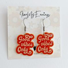 red and orange earrings with good vibes only written on the back in white letters