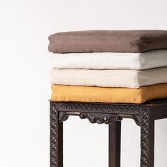 a stack of four pillows sitting on top of a wooden stool