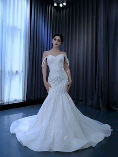 a woman standing in front of a window wearing a wedding dress with sequins on it