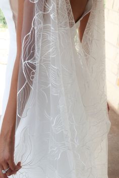 the back of a woman's wedding dress with sheer white fabric and flowers on it