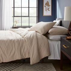 a bedroom with blue walls and white linens on the bed, along with two nightstands