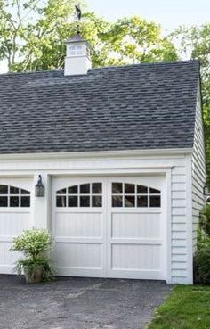 a white garage with two windows and a black roof