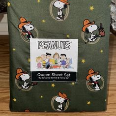 the peanuts queen sheet set is green with cartoon characters on it and stars in the background