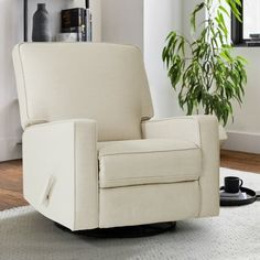 a living room with a white chair and a potted plant on the floor next to it