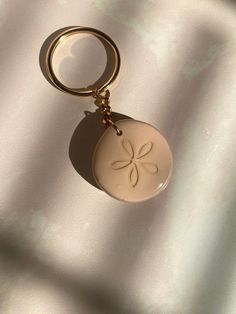 a white keychain with a flower on it