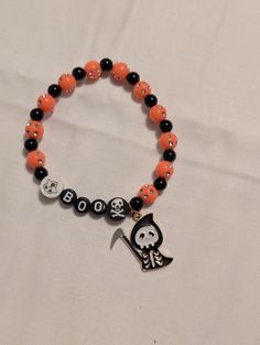 A hand-crafted Halloween themed beaded bracelet with orange, black, and white beads and a cute reaper charm. Halloween Diy Bracelets, Novelty Black Beaded Bracelets For Halloween, Novelty Orange Bracelets For Halloween, Halloween Novelty Orange Bracelets, Handmade Casual Halloween Jewelry, Casual Handmade Jewelry For Halloween, Casual Handmade Halloween Jewelry, Halloween Themed Handmade Beaded Bracelets, Handmade Halloween Themed Beaded Bracelets