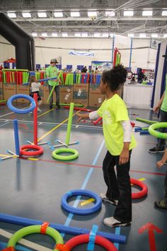 a young boy standing on top of a floor surrounded by plastic rings and hoses