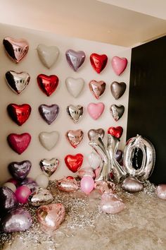 there are many heart shaped balloons on the wall