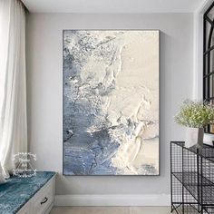 an abstract painting hangs on the wall in a white and gray room with blue accents