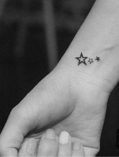 a small star tattoo on the left inner wrist is shown in this black and white photo