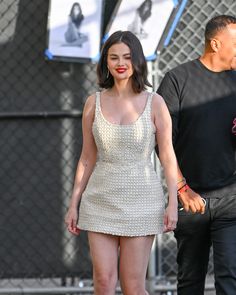 a woman in a short white dress walking next to a man