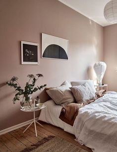 a bed sitting in a bedroom next to a window filled with plants and pictures on the wall