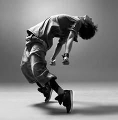 a man is doing a trick on a skateboard in black and white with his legs spread out