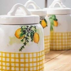 three yellow and white canisters with lemons painted on them