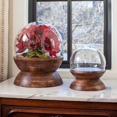 two glass vases with flowers in them sitting on a table next to a window