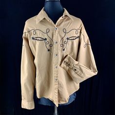 Vintage Panhandle Slim a Westmoor Product retro Western wear cowboy shirt. Light brown gabardine cotton fabric with diamond shaped snaps up the front and embroidered rope decoration front and back. 2 front pockets with stars at the ends. All in excellent condition we find no issues. Marked size XL so this might be a boys shirt please check the measurement (especially sleeve length and the shirt's length). Chest: 43" Back neck to cuff: 34" Back of neck to hem: 26" Sleeve: 24" Length: 24.5" Excellent condition no issues. Sale supports Vermont's PuppeTree. This was part of the puppet company's costume collection. Thank you. Oklahoma Western Shirt, Western Style Embroidered Cotton Shirt, Cowboy Shirt, Rope Decor, Cowboys Shirt, Cowgirl Shirts, Costume Collection, Cowgirl Outfits, Boys Shirts