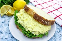 a sandwich on a plate with lemons and greens