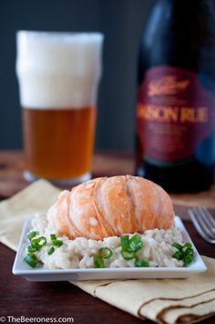 a plate topped with rice and meat next to a glass of beer