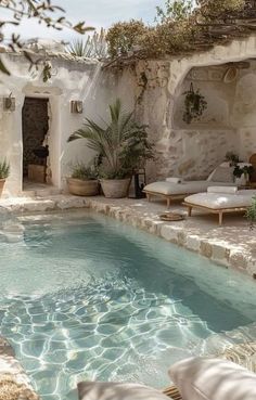 an outdoor swimming pool with lounge chairs and potted plants