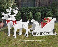 two white wooden sleighs with presents on them in front of a house