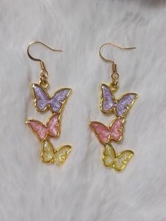 Elevate your style with a touch of royalty wearing these enchanting handmade resin butterfly dangle earrings. The rich combination of purple, pink, and yellow creates a regal and captivating accessory that adds a dash of sophistication to any ensemble. -crafted with UV Resin, Alloy Hypoallergenic All earrings are handmade by me and there may be minor variations. Colors may vary slightly from photos. Contact me if you have any questions.  Care instructions: Clean with a soft jewelry polishing clo Soft Jewelry, Resin Butterfly, Butterfly Dangle Earrings, Butterfly Earring, Butterfly Earrings Gold, Earring Gift, Yellow Butterfly, Butterfly Jewelry, Gold Butterfly