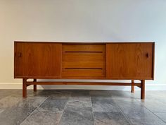 a wooden sideboard sitting on top of a tiled floor next to a white wall