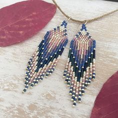 a pair of beaded earrings hanging from a string on top of a wooden table