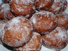 a pile of powdered sugar covered doughnuts in a white bowl on a table