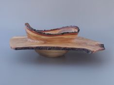 a wooden bowl sitting on top of a table next to a gray wall and floor