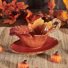 a red saucer sitting on top of a table next to small orange pumpkins