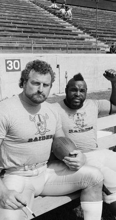 two men sitting on a bench at a football game