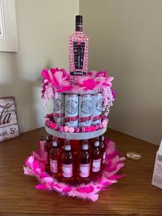 a cake made to look like a tower with bottles on top and pink feathers around it