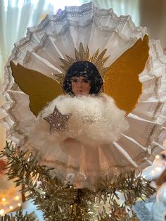 an angel ornament on top of a christmas tree