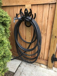 a bunch of black hoses hanging from a wooden fence