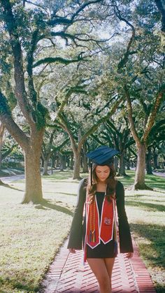 a woman walking down a brick path with trees in the background and grass on either side