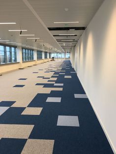 an empty room with blue and white carpeting on the floor next to large windows