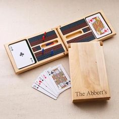 an open wooden box with playing cards and dominos in it on a white surface