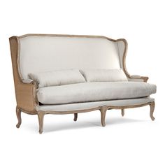 an old style couch with white linen and wood trimmings on the back end