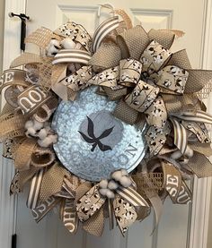 a wreath that is hanging on the front door with ribbon around it and an image of a bird