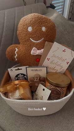 a stuffed teddy bear sitting in a basket filled with treats and cards on a couch