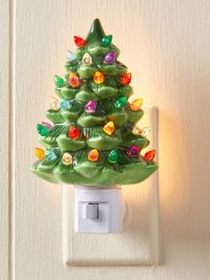 a green christmas tree light switch cover on a white wall with a small outlet in the middle