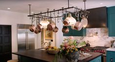 a kitchen filled with lots of pots and pans hanging from the ceiling over an island