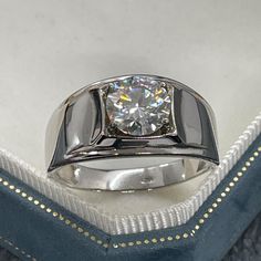 a diamond ring sitting on top of a blue velvet case in a white gold and silver setting