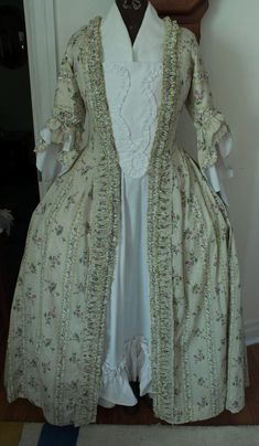 A historic style handmade Robe a La Franchise style gown stomacher and petticoat, in the rococo/colonial era style. The dress has been shown over stays/bumroll/panniers to achieve the era's silhouette, the bodice is not boned. The dress has pocket slits and a pleated sack back. The pattern is based on reference material from Fort Louisborg. The bodice is open front, meant to be pinned to the stomacher as shown. The lining is sheer linen, the outer material is a historically styled cotton calico. Fitted Victorian Marie Antoinette Dress, Fitted Victorian Baroque Dress In Marie Antoinette Style, Fitted Victorian Dress In Marie Antoinette Style, Spring Victorian Dress Historical Design For Costume, Spring Victorian Costume Dress With Historical Design, Spring Victorian Dress Costume With Historical Design, Spring Victorian Dress With Historical Design For Costume, Spring Regency Style Victorian Dress Costume, White Rococo Victorian Dress Costume