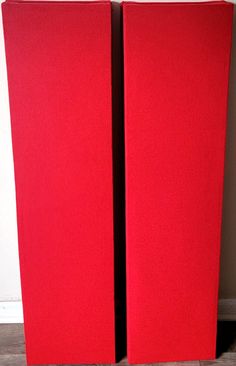 two red speakers sitting next to each other on the floor in front of a wall