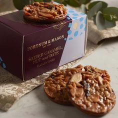 two cookies sitting on top of a table next to a box filled with nuts and raisins