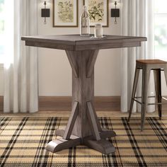 a wooden table sitting on top of a rug next to two stools in front of a window