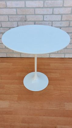 a white table sitting on top of a hard wood floor next to a brick wall