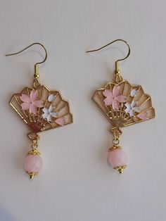 Dangle drop earrings with stainless steel hooks,  chinese  fan with pink cherry blossom flowers and 8mm pink quartz bead. A unique gift or mini indulgence for yourself, they are a perfect addition to any outfit. Very lightweight to wear. Thank you for visiting my shop! If there is an item that you fancy but you would like an alteration made, please let me know with the details and I will try to accommodate your request. Alterations can include, but are not limited to, resizing, clasp changes, charm changes, preference for a different base metal: silver, copper, brass or gold. Where alterations are made, please allow up to 2 extra business days for your items to be sent. All items are handmade by me with care, love and attention. To ensure that you get the most out of your jewellery please: Cherry Blossom Flower, Chinese Fan, Pink Sakura, Cherry Blossom Flowers, Pink Cherry, Fan Earrings, Earrings Pink, Quartz Rose, Pink Earrings